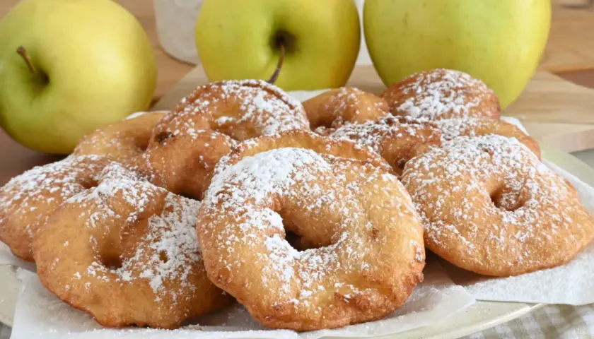 Frittelle di mele dorate e spolverate di zucchero a velo, pronte per essere gustate.