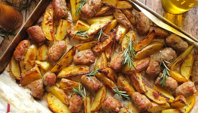 Salsiccia e patate al forno, dorate e profumate al rosmarino, pronte per essere gustate.
