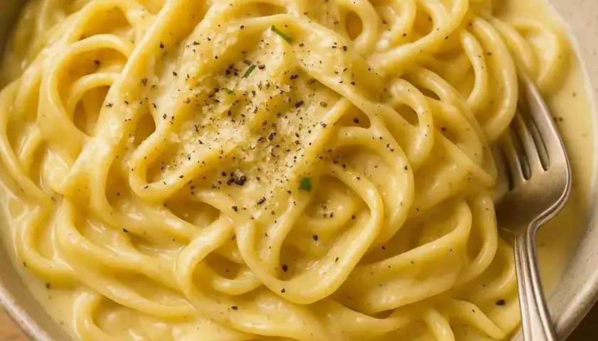 Un piatto invitante di pasta in bianco, condita con pepe nero macinato fresco e parmigiano grattugiato.