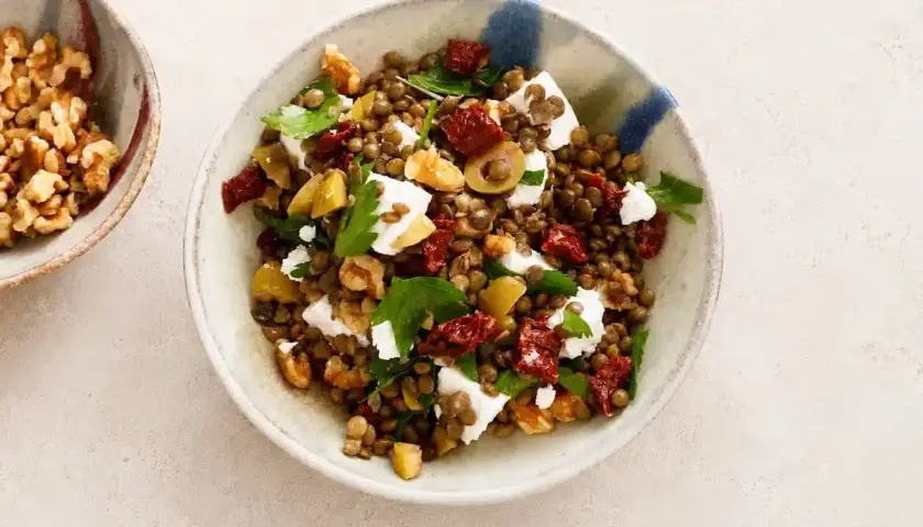 Insalata di lenticchie estiva con feta, pomodori secchi, olive e noci. Fresca e saporita, perfetta per un pasto leggero.