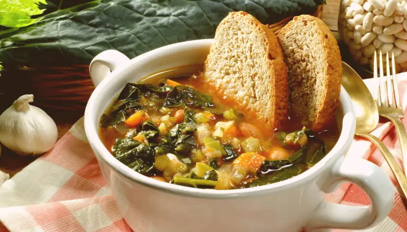 Una ciotola fumante di zuppa di cavolo nero, con pane tostato e fagioli, pronta per essere gustata.