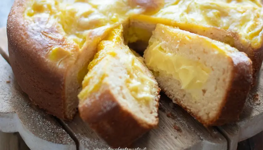 Torta al limone velocissima con crema gialla e soffice impasto, tagliata a fette su un tagliere di legno.