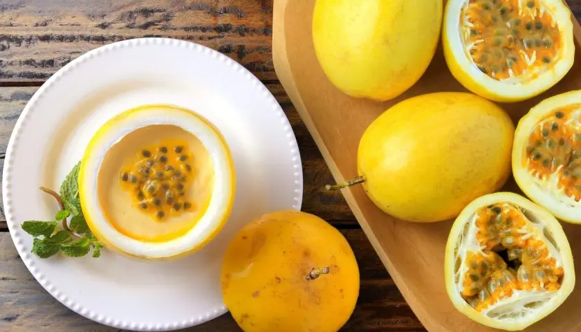 Deliziosa mousse al limone servita in un frutto della passione, guarnita con menta. Frutti della passione freschi completano la scena.