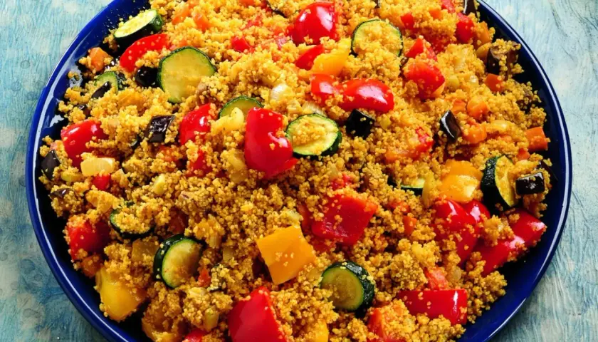 Un piatto colorato di cous cous con verdure miste: peperoni rossi e gialli, zucchine e melanzane. Una deliziosa ricetta cous cous.