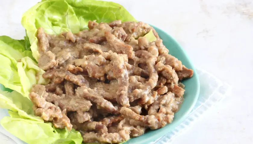 Straccetti di manzo succulenti serviti su foglie di lattuga fresca, un piatto invitante e saporito.