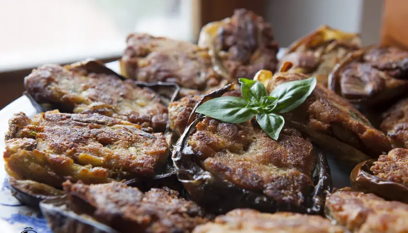 Melanzane ripiene calabresi dorate e gustose, guarnite con basilico fresco. Un piatto tradizionale che profuma di casa.