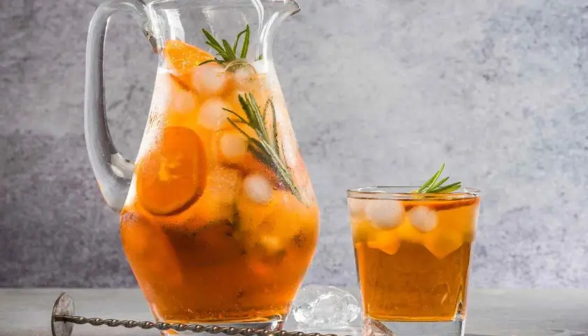 Rinfrescante freddo fatto in casa con arancia e rosmarino, servito in caraffa e bicchiere con ghiaccio.