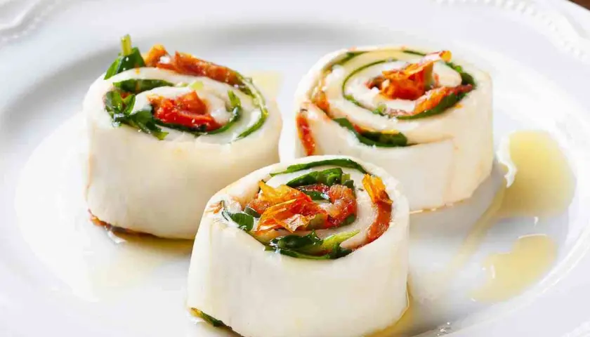 Rotolini di sfoglia di mozzarella come riempirla con pomodori secchi e basilico, conditi con olio.