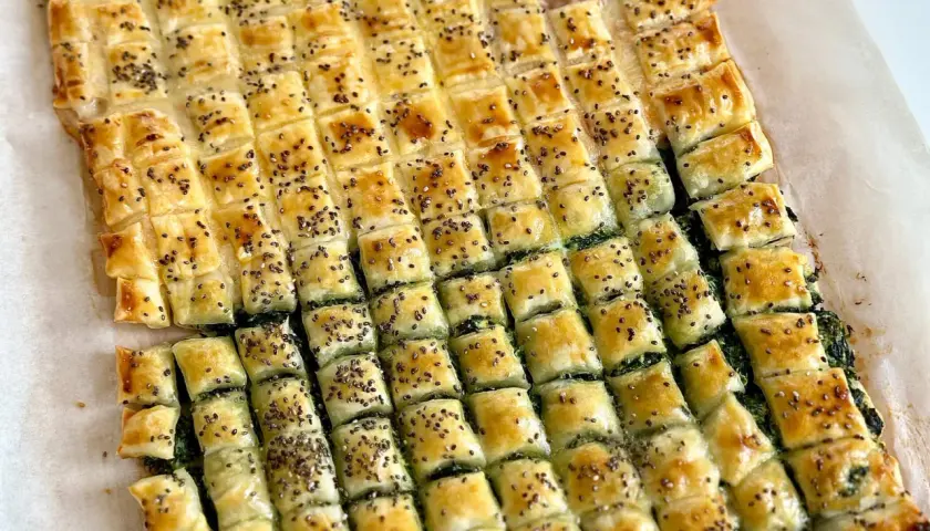 Pasticcio di pasta sfoglia rettangolare con ripieno verde, tagliato a quadretti e cosparso di semi. Un'idea su come farcire pasta sfoglia rettangolare.