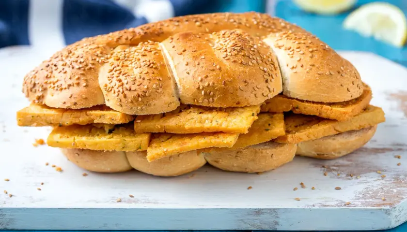 Pane morbido con semi di sesamo farcito con fette dorate di pane e panelle, un classico street food siciliano.