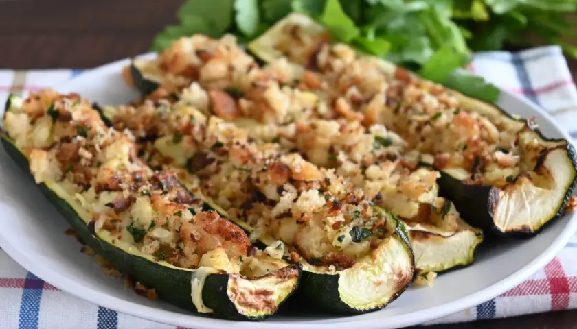 Zucchine ripiene velocissime, dorate e croccanti, servite su un piatto bianco con un contorno di prezzemolo fresco.