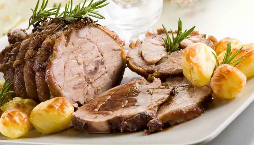 Succulento arrosto di vitello, affettato e servito con patate arrosto e rametti di rosmarino.