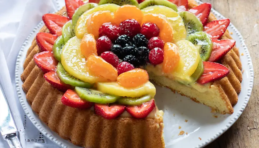 Una deliziosa crostata di frutta, con fragole, kiwi, mandarini, lamponi e mirtilli su una base di crema pasticcera.