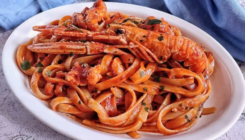 Un piatto invitante di linguine agli scampi, condite con un sugo rosso e guarnite con prezzemolo fresco.