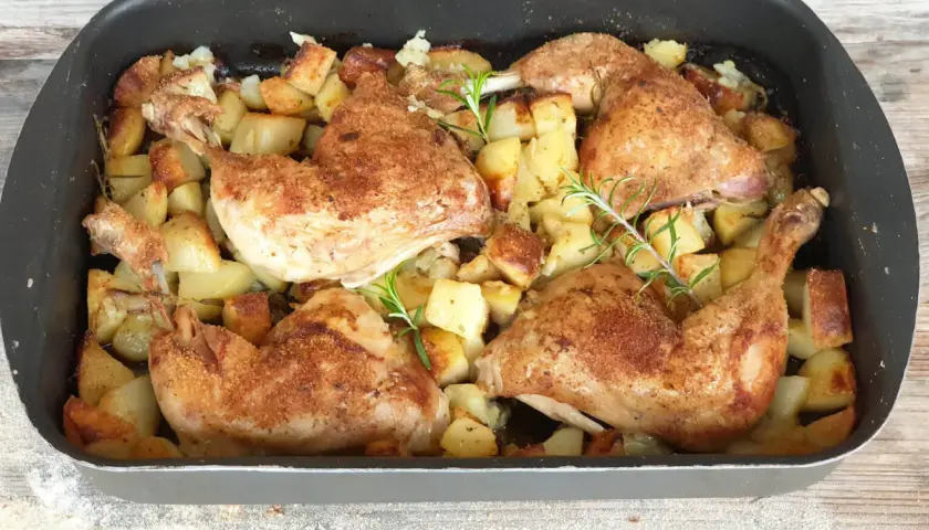 Succulento pollo al forno con patate dorate e rosmarino, pronto per essere gustato.