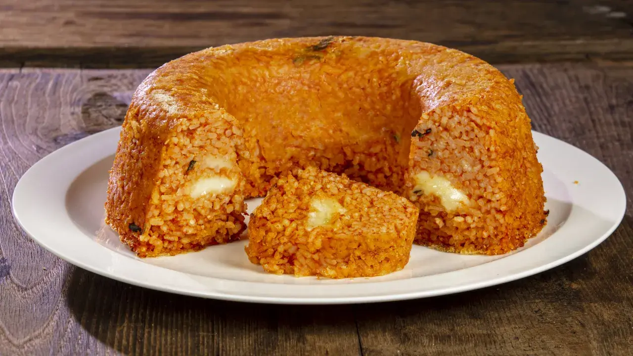 Un invitante timballo di riso, dorato e ripieno di formaggio filante, pronto per essere gustato.