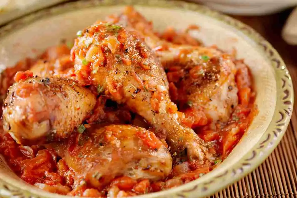Pollo alla cacciatora succulento in una ciotola, con pezzi di pollo dorati immersi in un sugo rosso ricco di pomodoro e spezie.