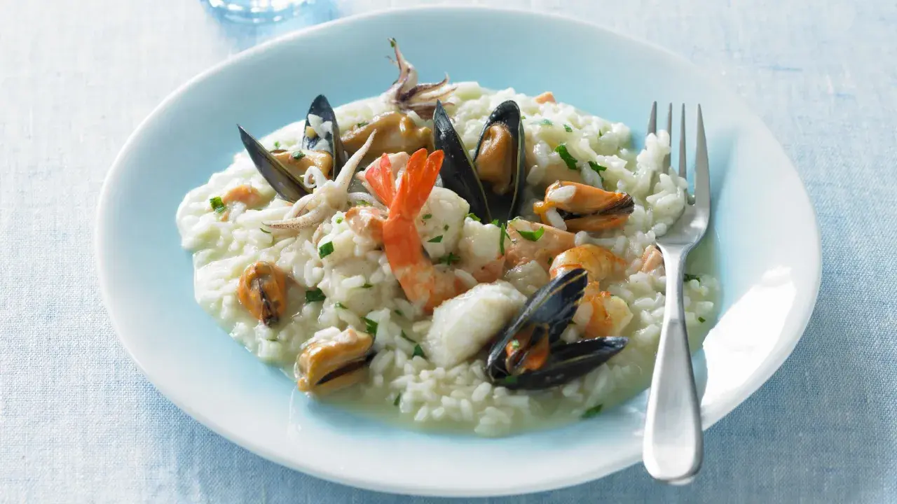 Un cremoso risotto alla pescatora, ricco di cozze, gamberi e calamari, pronto per essere gustato.