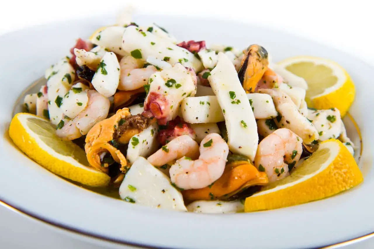 Deliziosa insalata di mare con gamberi, calamari, polpo e cozze, condita con prezzemolo e limone.