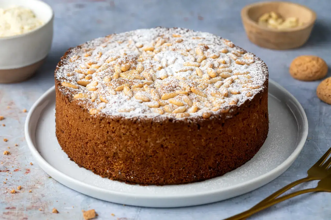 Torta rustica con farina di mandorle, guarnita con pinoli e zucchero a velo. Perfetta per ogni occasione.