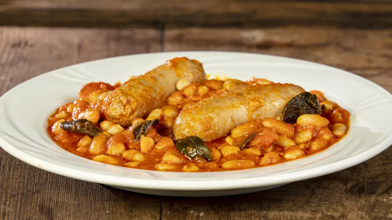Salsiccia e fagioli in umido, un piatto rustico e saporito, servito su un piatto bianco.