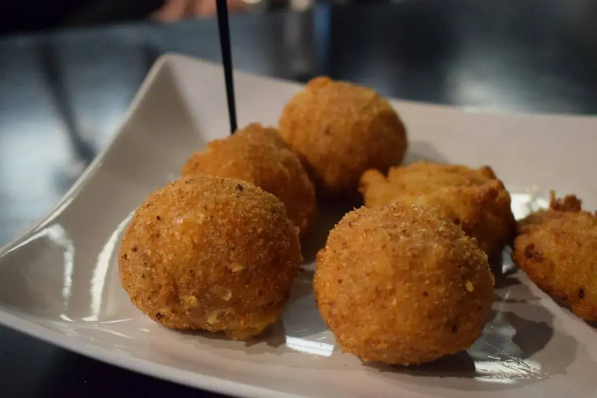 Deliziosi arancini di riso dorati e croccanti, serviti su un piatto bianco.