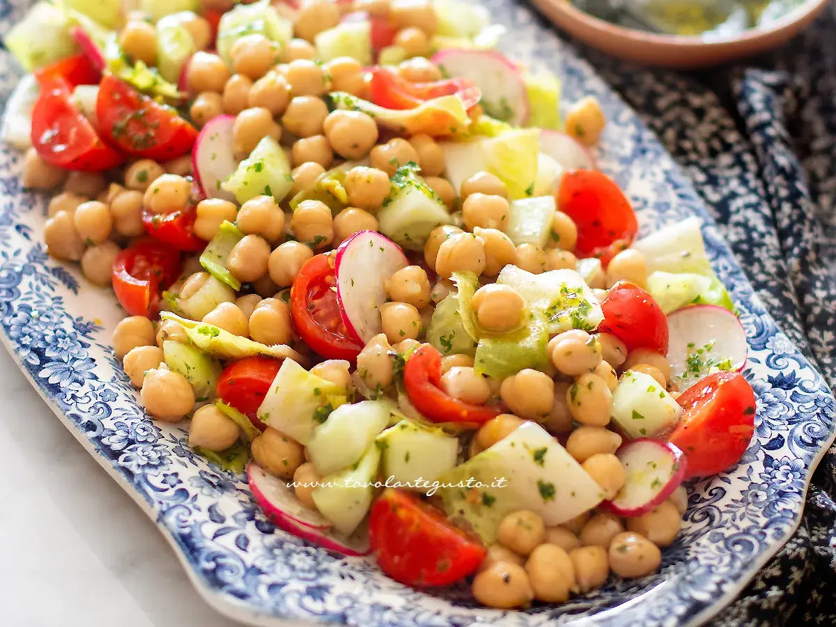 Un'insalata di ceci fresca e colorata con pomodorini, cetrioli e ravanelli, condita con erbe aromatiche.