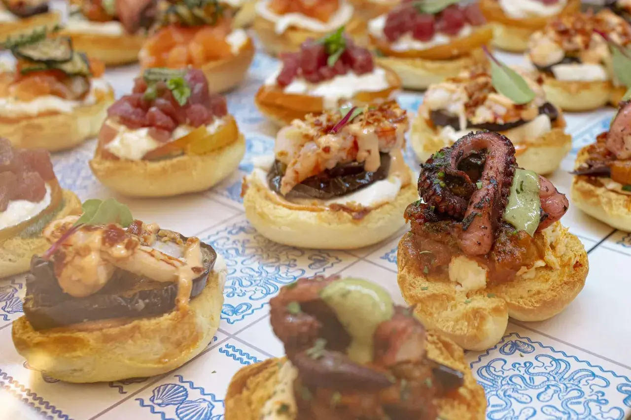 Varietà di antipasti di pesce su pane tostato: polpo grigliato, gamberi, tonno e salmone. Un'esplosione di sapori marini.
