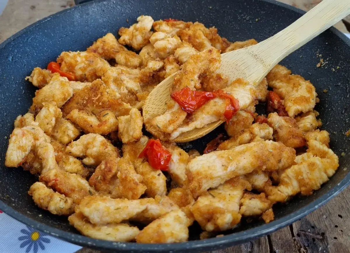 Straccetti di pollo saporiti cotti in padella con pomodorini e erbe aromatiche, pronti per essere gustati.