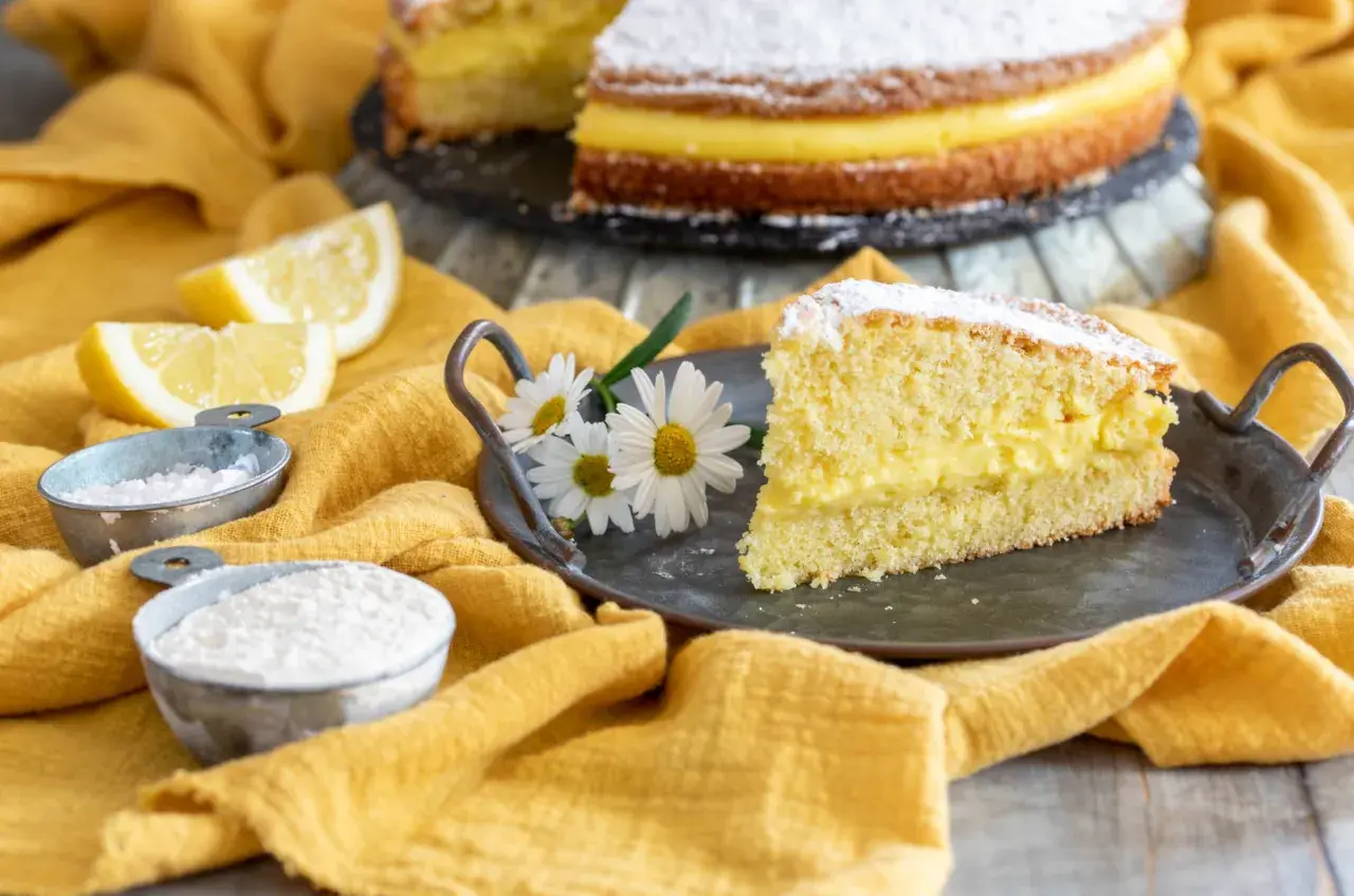 Una fetta di torta paradiso, soffice e farcita di crema, pronta per essere gustata. La ricetta perfetta per un dolce fatto in casa.