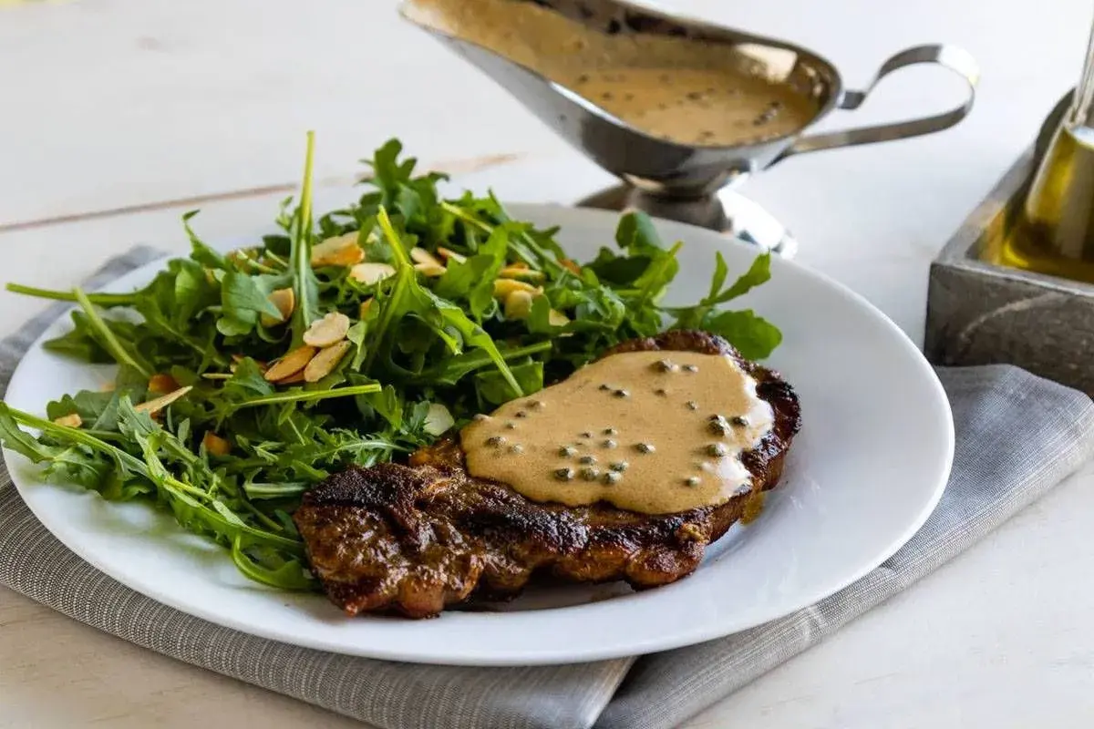 Un succulento filetto al pepe verde, nappato con la sua salsa cremosa, accompagnato da un'insalata fresca di rucola e mandorle.