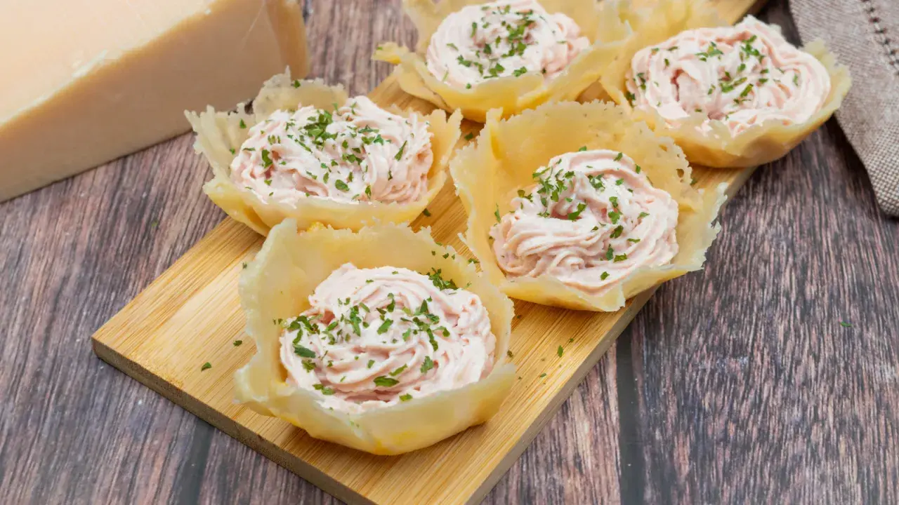 Deliziosi cestini di parmigiano ripieni di crema rosa e guarniti con erba cipollina. Un antipasto elegante e gustoso.