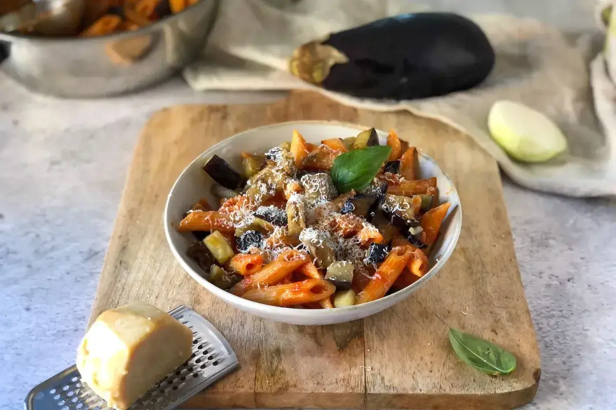 Piatto di pasta alla norma, un classico della ricetta della nonna, con melanzane, pomodoro e ricotta salata grattugiata.