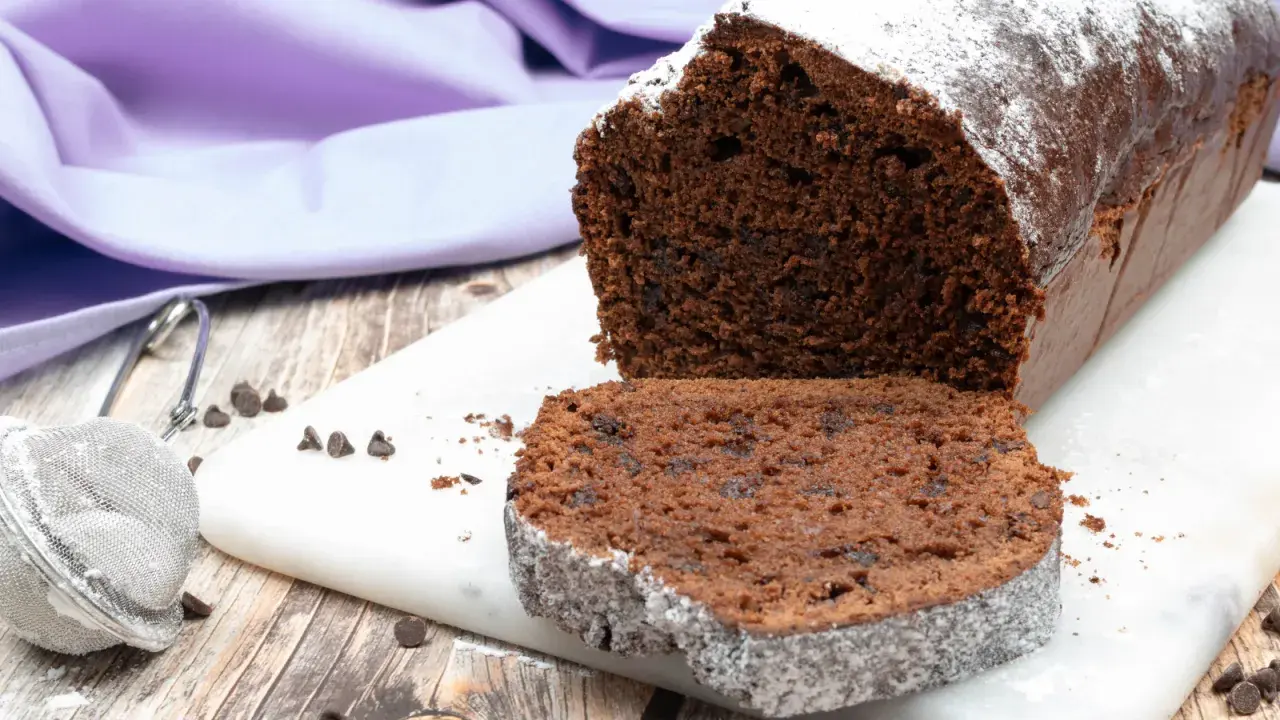 Un soffice plumcake al cioccolato, cosparso di zucchero a velo, pronto per essere gustato.