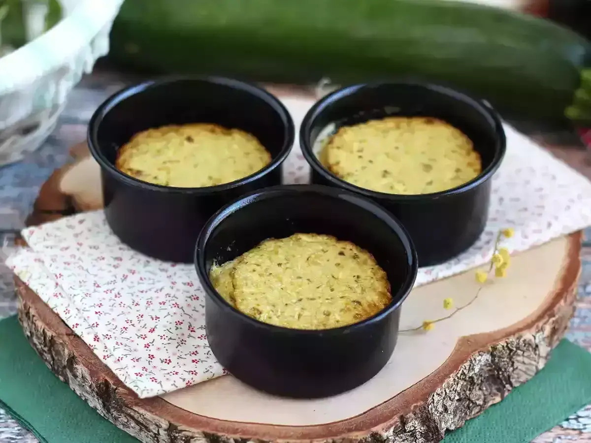 Tre deliziosi flan di zucchine appena sfornati in stampini neri, pronti per essere gustati.