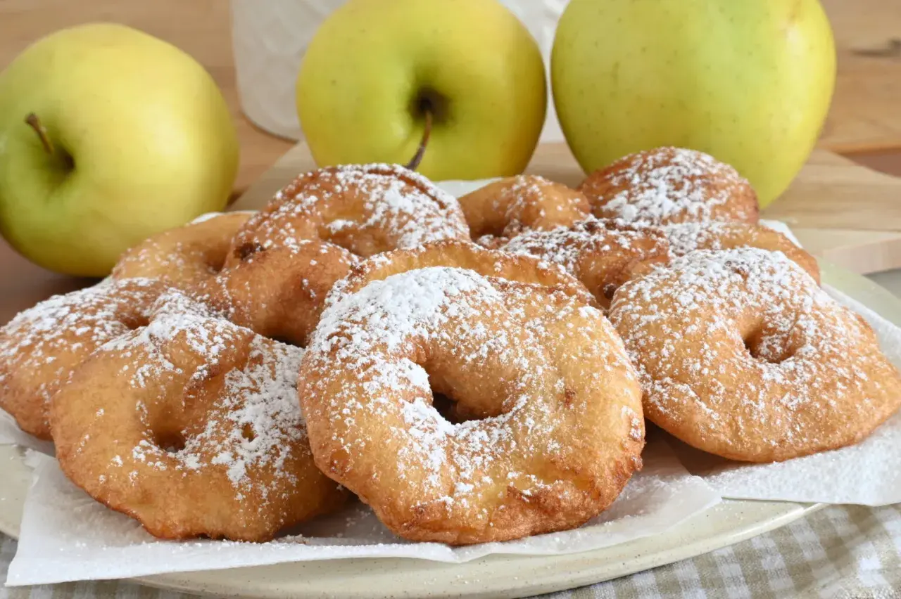 Frittelle di mele dorate e spolverate di zucchero a velo, pronte per essere gustate.