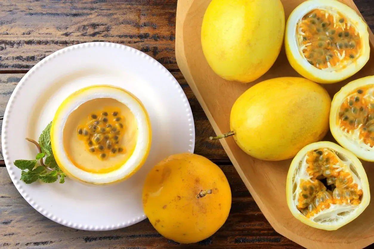 Deliziosa mousse al limone servita in un frutto della passione, guarnita con menta. Frutti della passione freschi completano la scena.