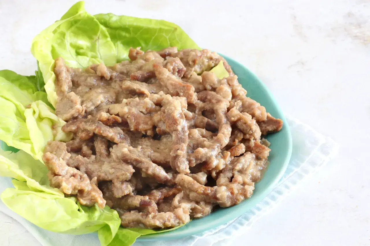 Straccetti di manzo succulenti serviti su foglie di lattuga fresca, un piatto invitante e saporito.
