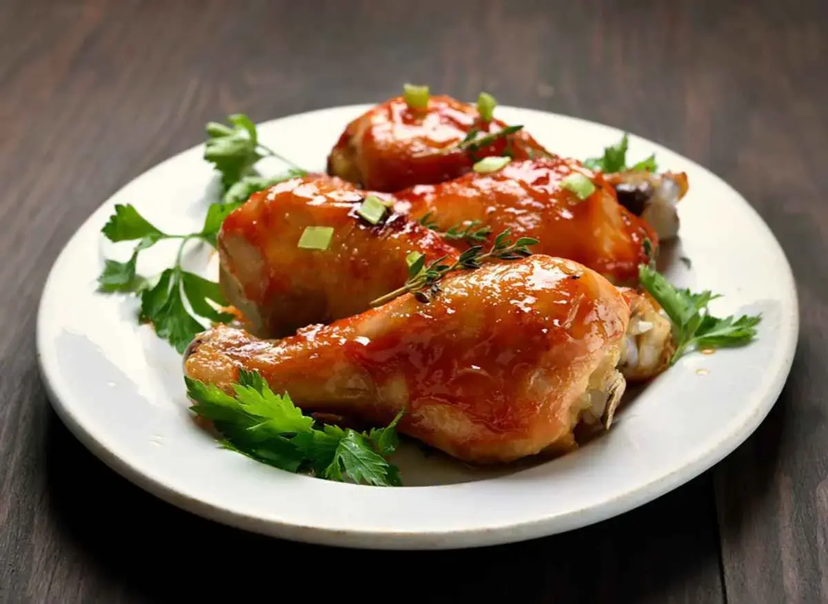 Tre cosce di pollo glassate, guarnite con prezzemolo e erbe aromatiche, pronte per essere gustate. Un delizioso pollo alla birra.