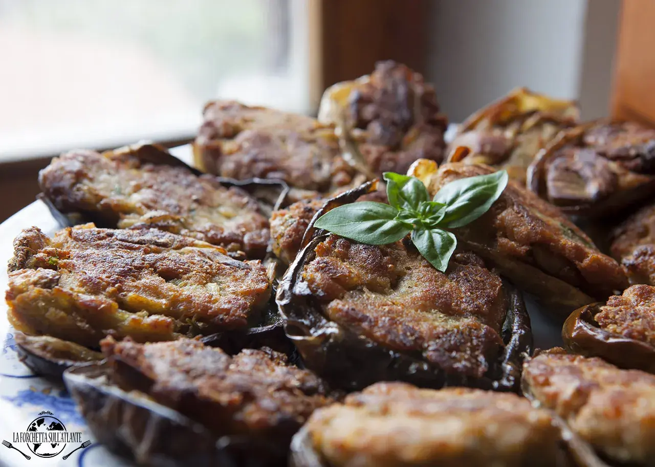 Melanzane ripiene calabresi dorate e gustose, guarnite con basilico fresco. Un piatto tradizionale che profuma di casa.