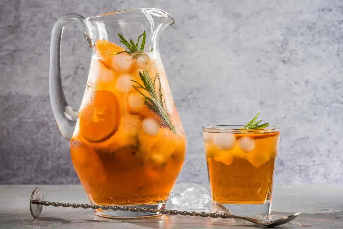 Rinfrescante freddo fatto in casa con arancia e rosmarino, servito in caraffa e bicchiere con ghiaccio.