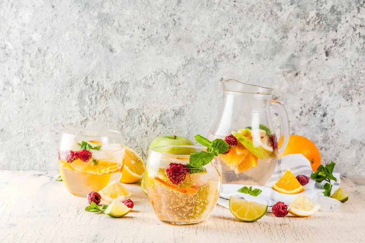 Sangria bianca ricetta: bicchieri e caraffa pieni di frutta fresca, ghiaccio e menta. Perfetta per l'estate!