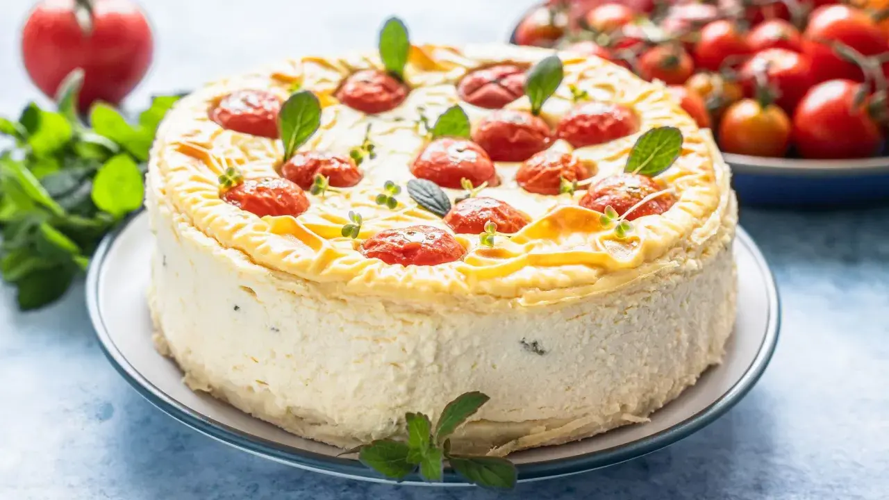 Cheesecake salata con taralli, decorata con pomodorini confit e basilico. Un'idea sfiziosa per un aperitivo o antipasto.