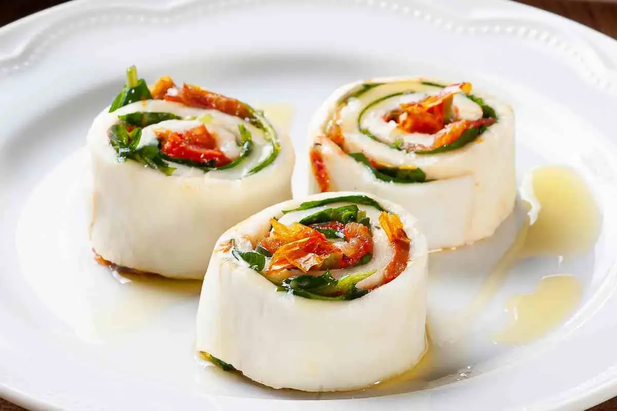 Rotolini di sfoglia di mozzarella come riempirla con pomodori secchi e basilico, conditi con olio.