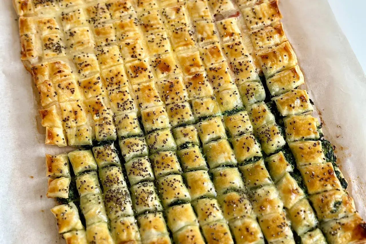Pasticcio di pasta sfoglia rettangolare con ripieno verde, tagliato a quadretti e cosparso di semi. Un'idea su come farcire pasta sfoglia rettangolare.