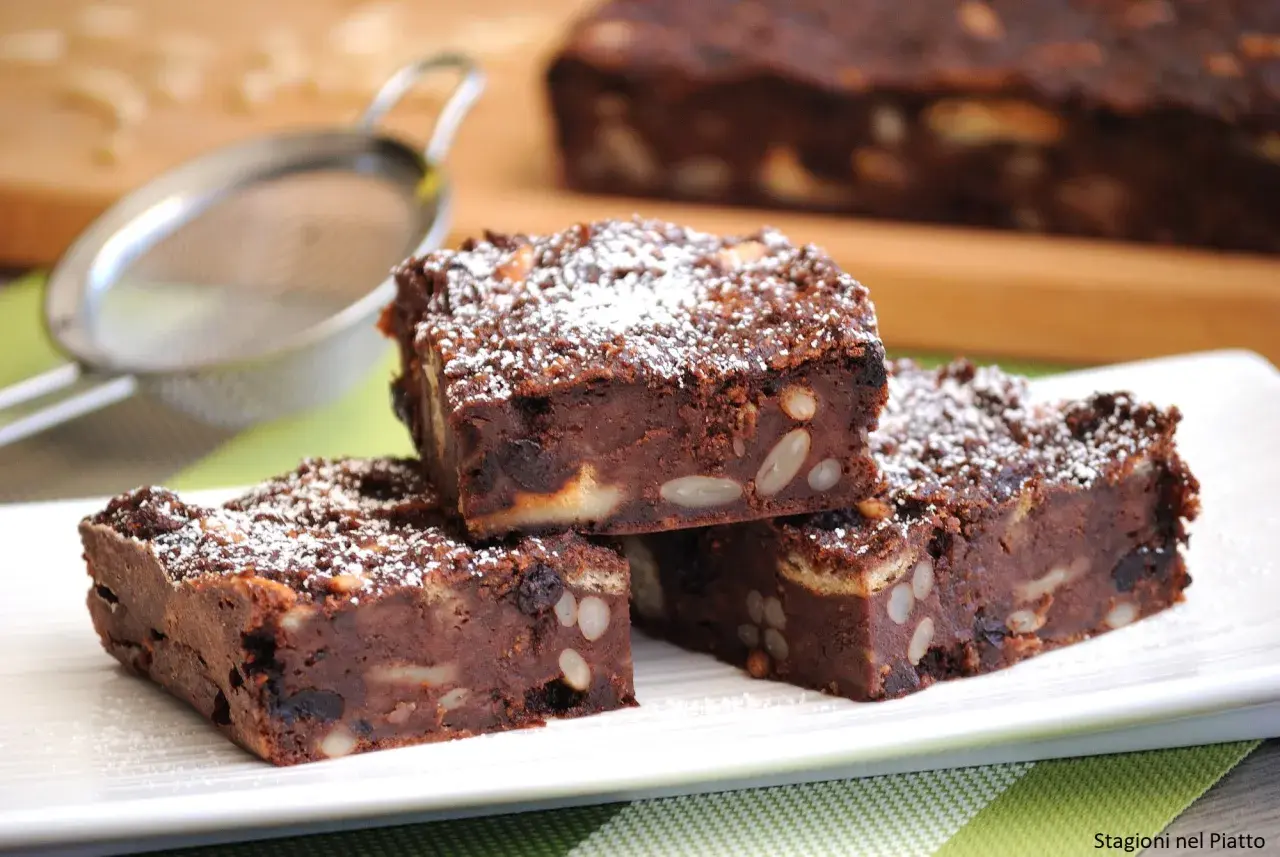 Fette di torta di pane al cioccolato, ricche di frutta secca e mandorle, spolverate di zucchero a velo.