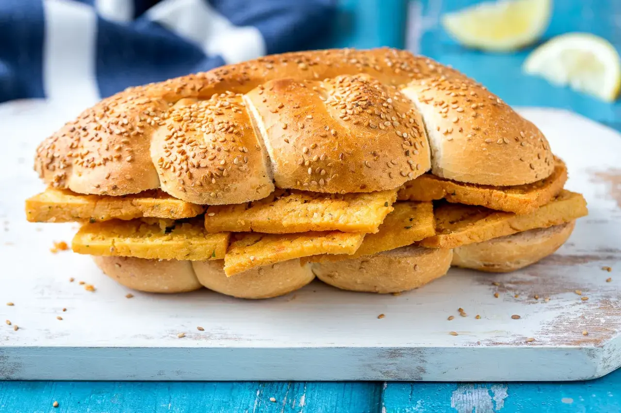 Pane morbido con semi di sesamo farcito con fette dorate di pane e panelle, un classico street food siciliano.
