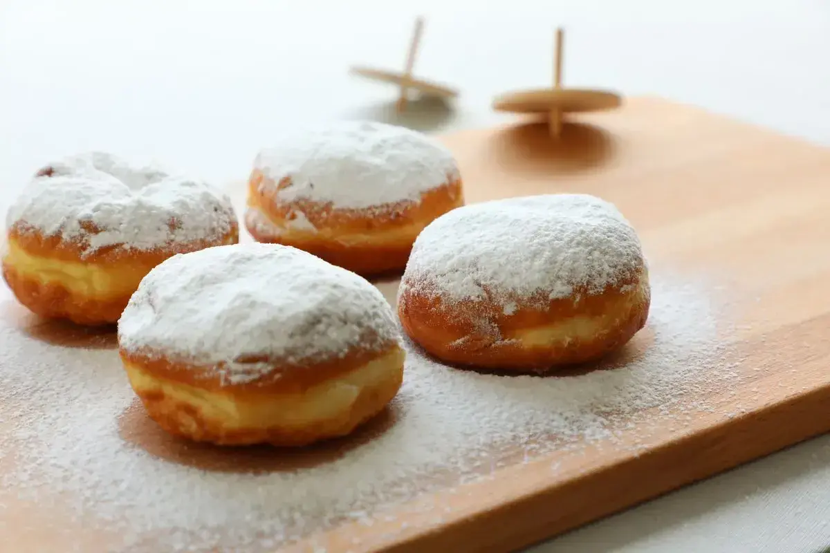 Quattro soffici bomboloni alla crema, cosparsi di zucchero a velo, invitano a un dolce momento.