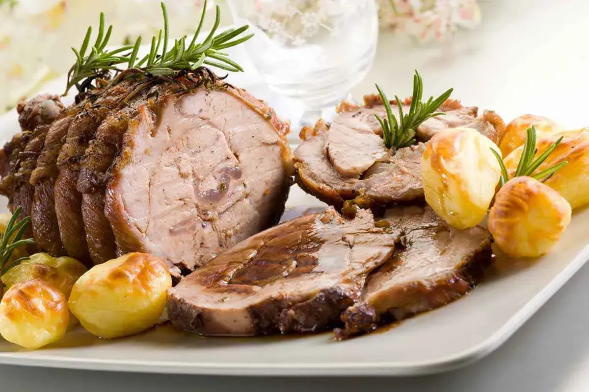 Succulento arrosto di vitello, affettato e servito con patate arrosto e rametti di rosmarino.