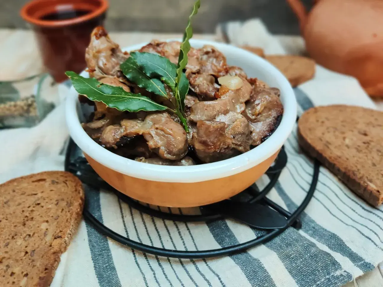 Durelli di pollo saporiti in ciotola, guarniti con foglie di alloro, accompagnati da fette di pane rustico.